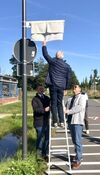 Friedhelm Fragemann enthüllt das neue Schild, BM Stockhoff und sein Stellvertreter Achim Schrecklein assistieren.